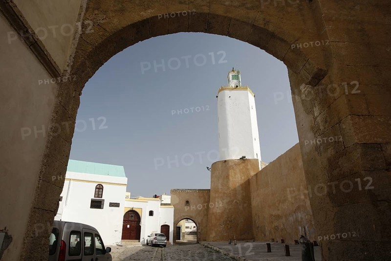 View through an archway of a white tower and sand-colored walls under a blue sky, El Jadida, Cité Portugaise, Morocco