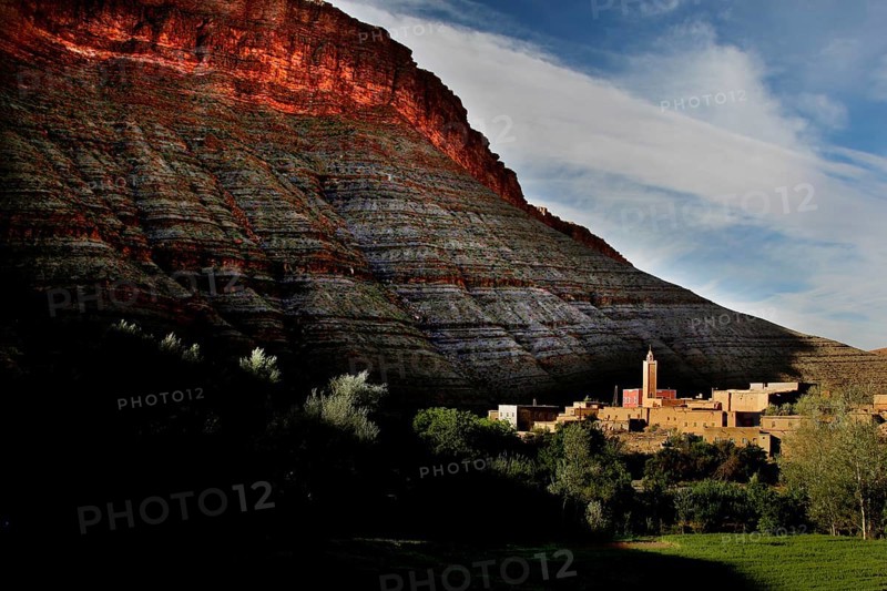 Gorge at sunset with silhouette of a building at the foot of glowing rocks, Dadès, Region, MA