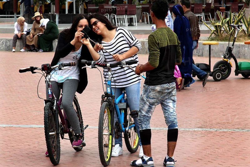 Friends enjoy a bike ride on Agadir promenade, laughing and relaxing, Agadir, Morocco