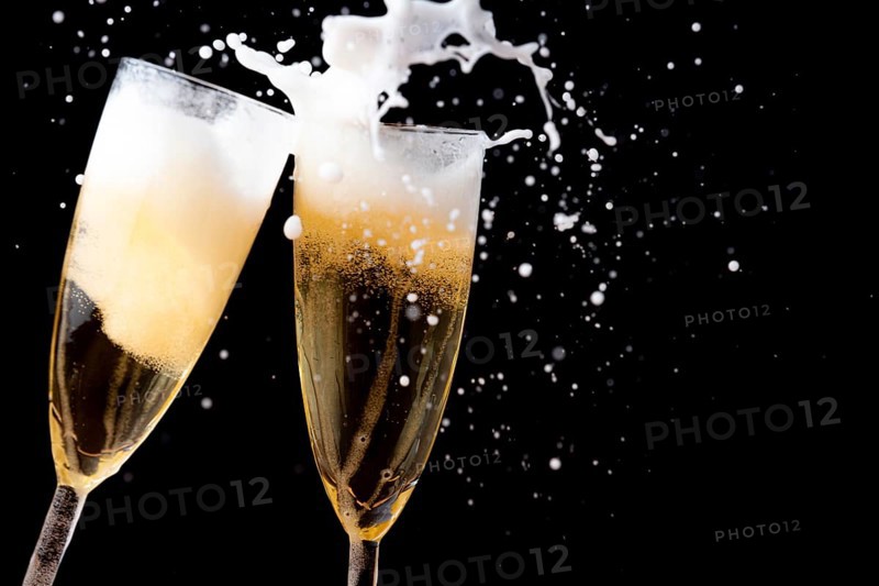 Two sparkling champagne glasses with foam against a dark background