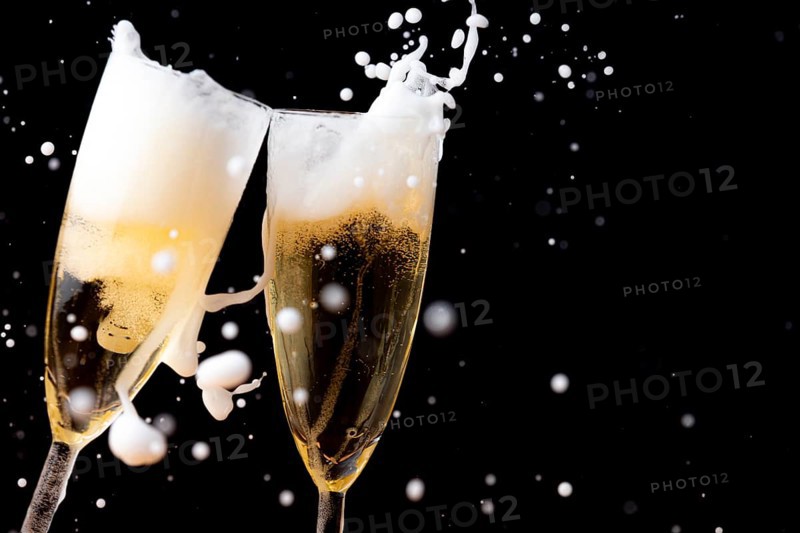 Two champagne glasses with sparkling and sparkling drink against a dark background