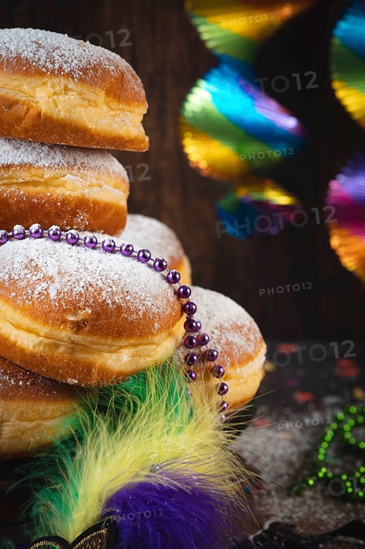 Close-up of Berliners with powdered sugar and pearl necklaces, colorful carnival atmosphere