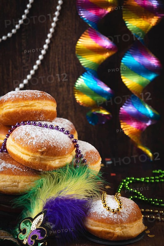Berliner with powdered sugar, decorated with pearl necklaces and colorful spirals against a dark background, carnival