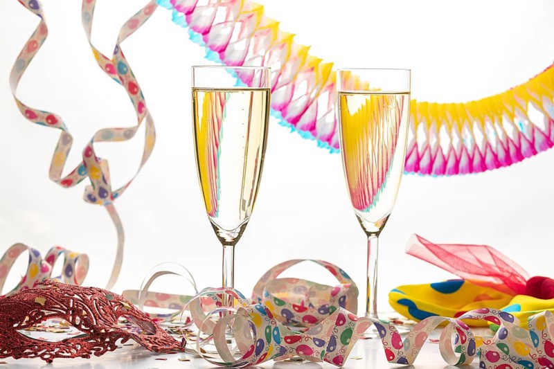 Two champagne glasses surrounded by decorative colorful streamers, carnival