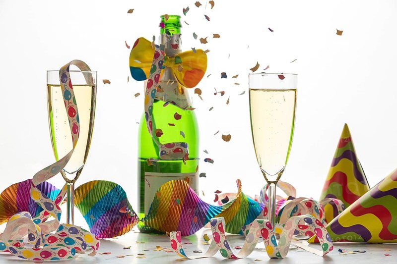 Champagne glasses and bottle surrounded by streamers and confetti, carnival