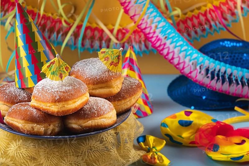 A plate of donuts decorated with party hats and colorful carnival accessories