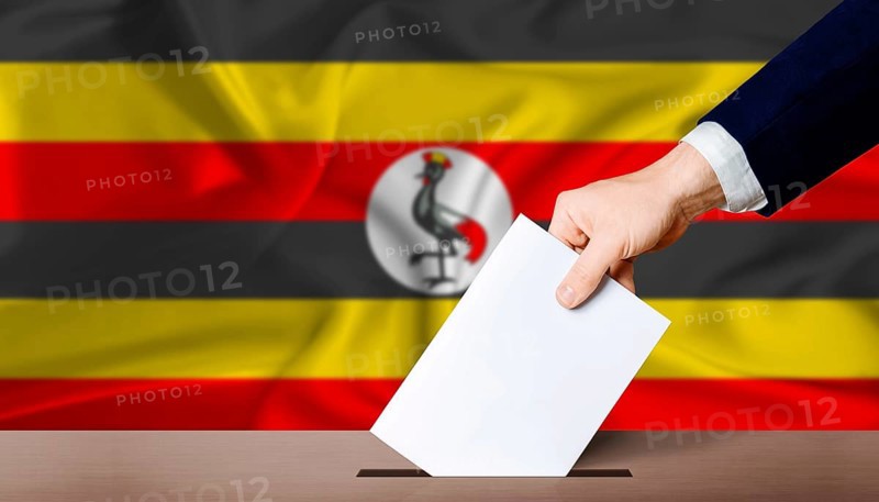 Uganda presidential vote 2026. Hand placing a ballot in ballot box with the Ugandan flag in the background