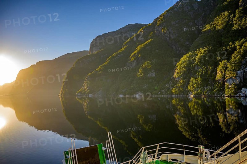 Tranquil fjord shore of Lyseford, illuminated by soft evening light with reflecting waters and dark mountains, view from the Columbus ferry, Lysefjord, Rogaland, Norway