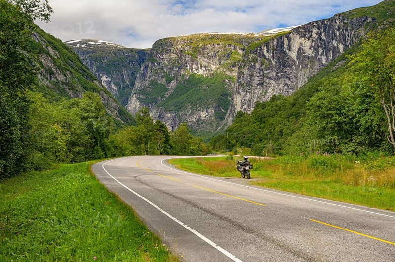 Åndalsnes, Møre og Romsdal province, Norway, Winding road with a motorcycle surrounded by green mountain scenery