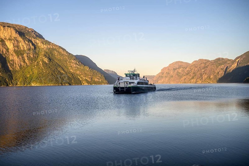 Columbus shipping company ferry moves through the Lysefjord with mountains in the background in the light of the morning sun, Lysefjord, Rogaland, Norway