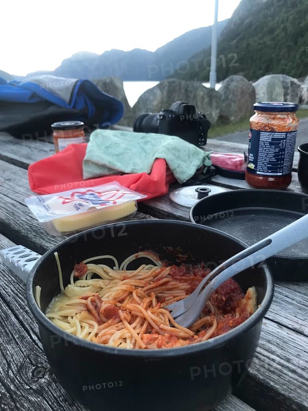 Rogaland Municipality, Norway, spaghetti with sauce on a wooden table in a rocky outdoor setting having dinner at Lysefjord