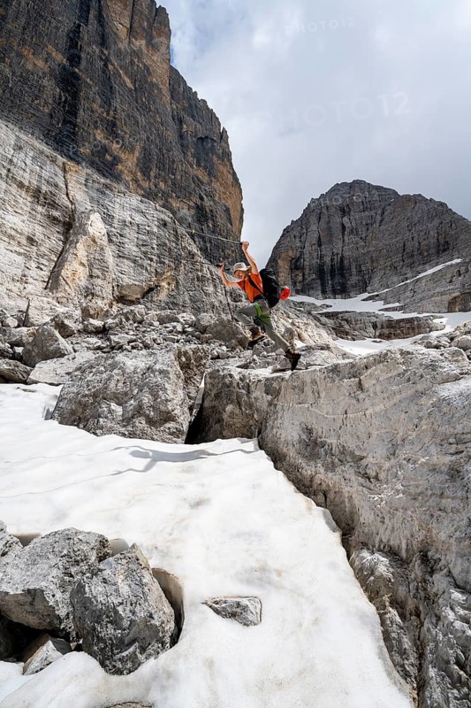 Mountaineer jumping off a rock into the snow, Camosci Valley, Brenta Mountains, Brenta-Adamello Natural Park, Trentino, Italy