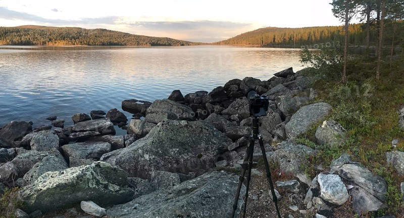 Drevsjø, Innlandet, Norway, scene of a photographer on a rocky lakeside at sunset, Gutulia National Park, Engerdal, Innlandet, Norway