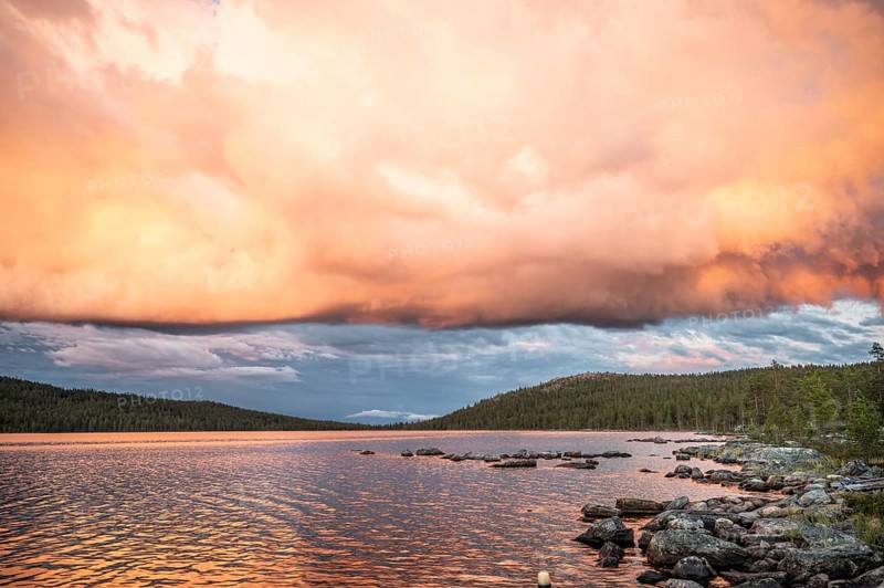 Evening cloud formation over Lake Gutulsjön illuminated by orange light, Gutulia National Park, Engerdal, Innlandet, Norway