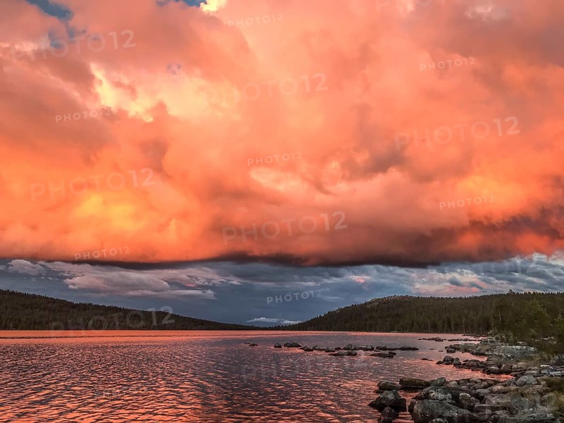Impressive sky with intense colors reflected in the calm lake, Gutulia National Park, Drevsjö, Engerdal, Innlandet, Norway