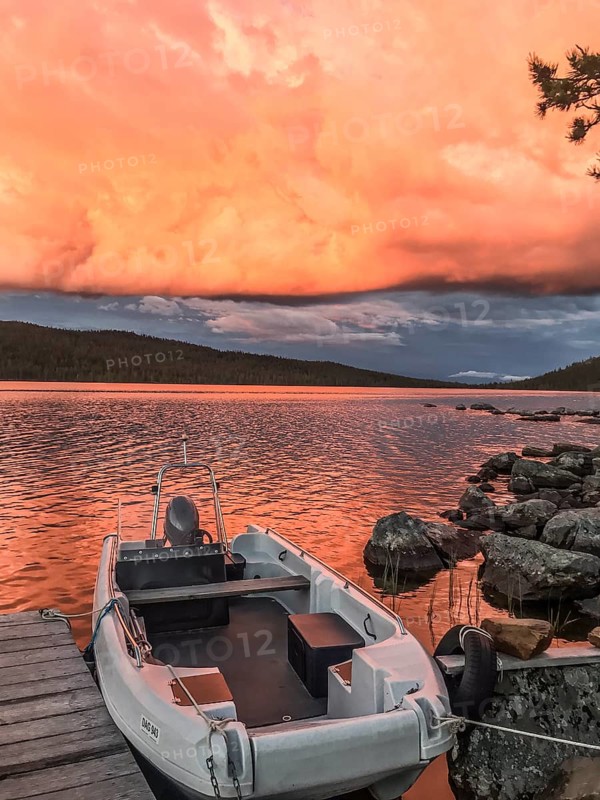 Boat moored on a jetty under a dramatic, colorful sky, Gutulia National Park, Engerdal, Innlandet, Norway