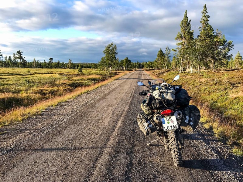 Idre, Dalarnas län, Sweden, BMW G 650 GS Sertao enduro motorcycle with full camping equipment on a country road at sunset with forest landscape