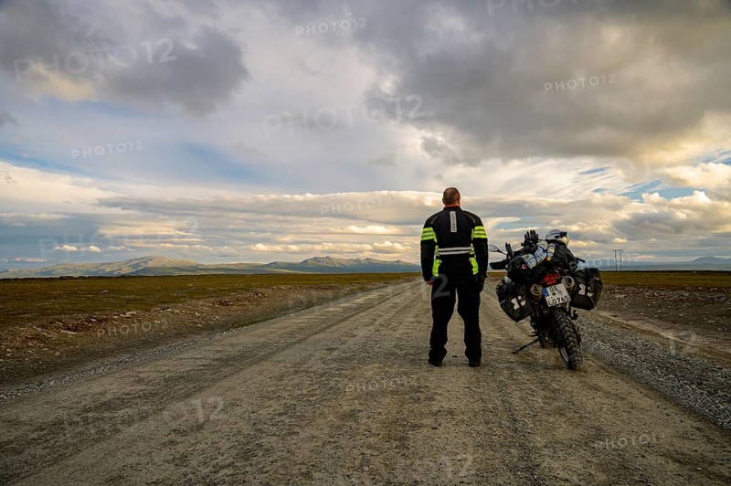 Falkvålen, Bruksvallarna, Jämtland, Sweden, BMW G 650 GS Sertao Enduro motorcyclist standing next to a BMW G 650 GS Sertao Enduro motorcycle on an empty country road with a wide view of the sky