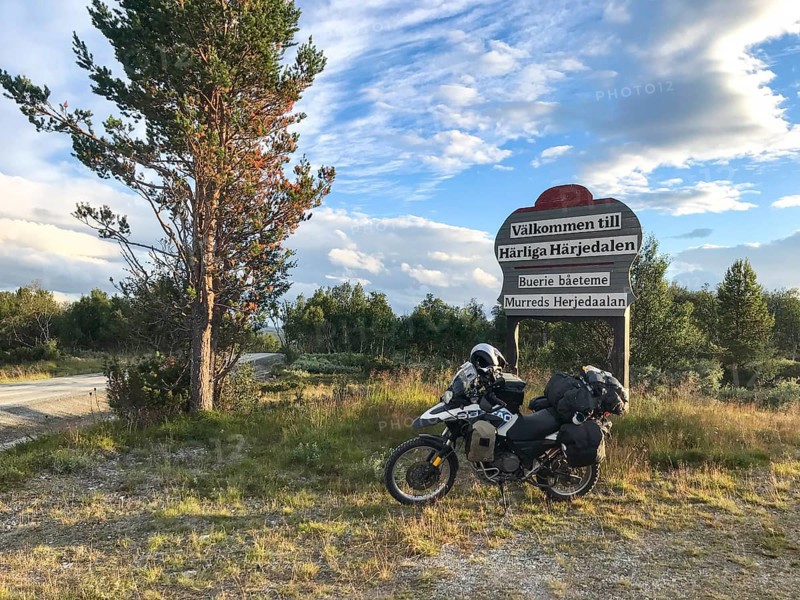 Funäsdalen, Jämtlands län, Sweden, Rural scene with a BMW G 650 GS Sertao Enduro motorcycle next to a welcome sign Wonderful Herjedalen under a clear sky