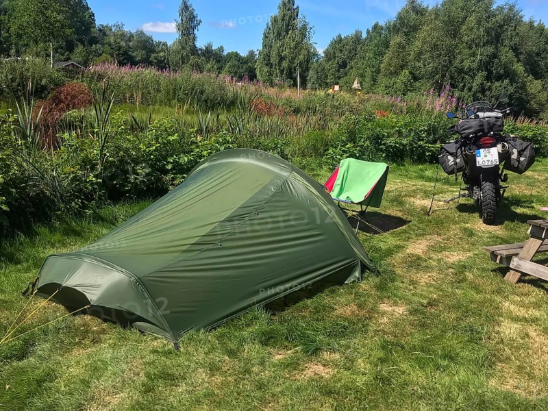 Växjö, Kronobergs län, Sweden, green campground with camping chair and BMW G 650 GS Sertao enduro motorcycle in a summer landscape, Asnen National Park