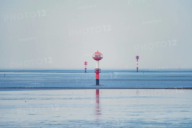 A red and white water buoy in the vast blue sea under a bright sky