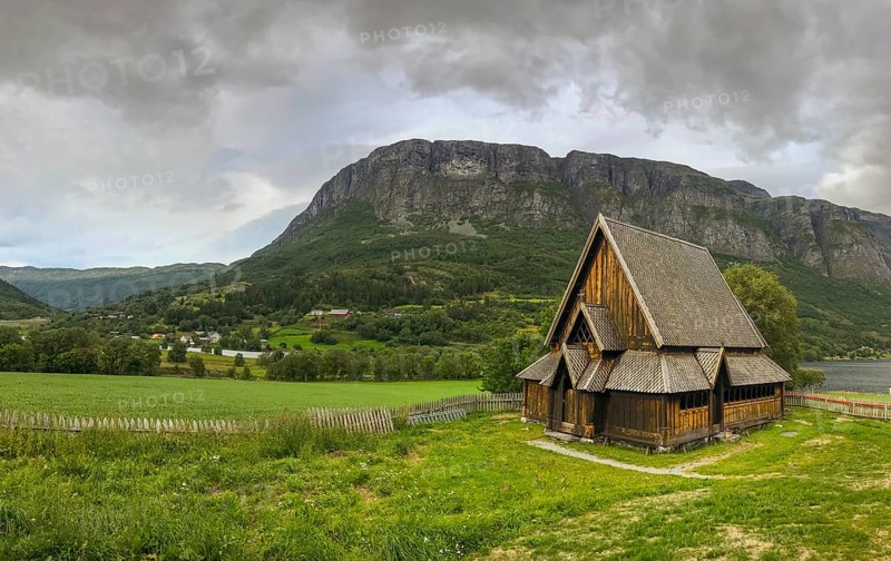 Øye, Innlandet, Norway, stave church in a green landscape with mountains in the background, wooden church in a vast, green landscape with mountains on the horizon