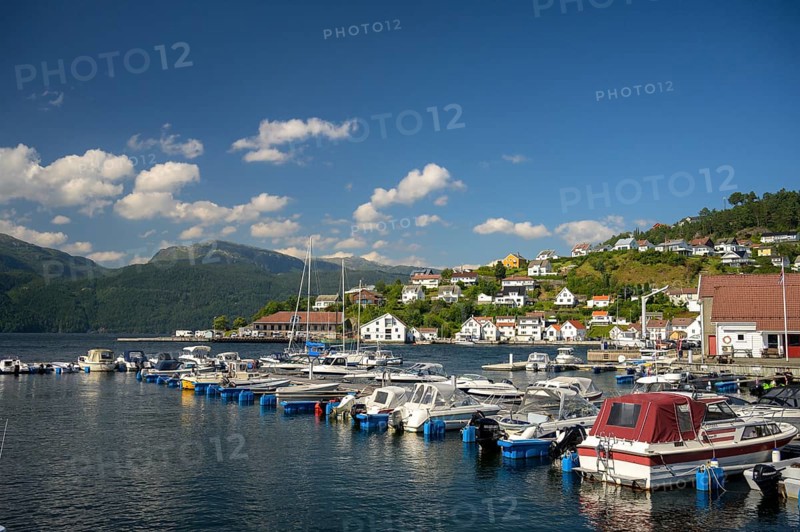 Sand, Rogaland municipality, Norway, boats in the harbor in front of a city with mountains and blue summer sky