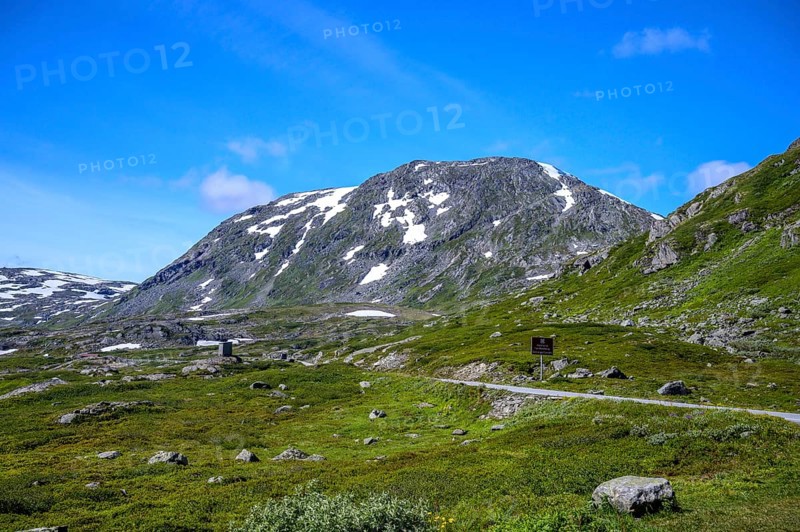 Geiranger, Møre og Romsdal province, Norway, rocky mountain landscape with green fields and blue sky