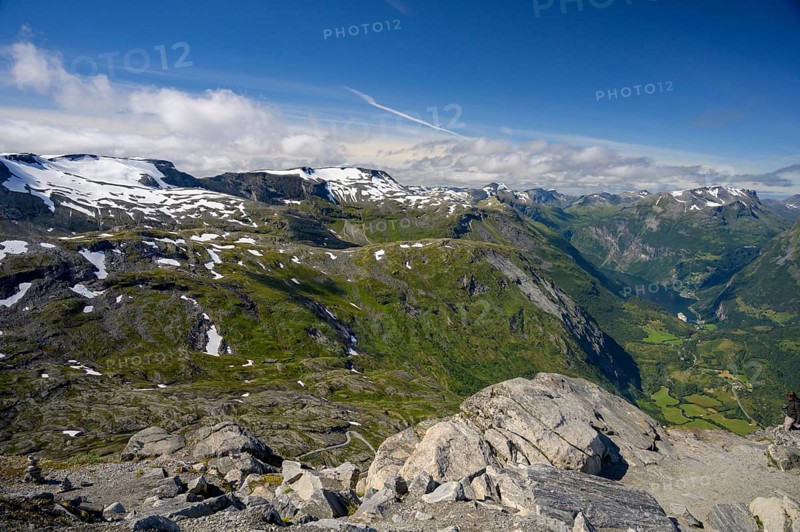 Geiranger, Møre og Romsdal province, Norway, view over snow-capped mountains and a green valley with the Geirtanger Fjord under blue sky, highest fjord view in Europe from the Geiranger Skywalk