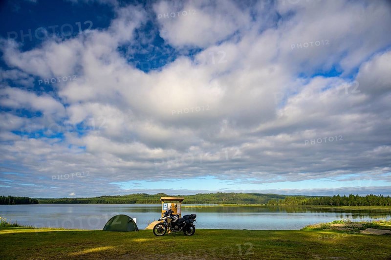 Rörström, Dorotea, Västerbotten, Sweden, motorcycle and tent on the shore of a large lake under a dramatic sky