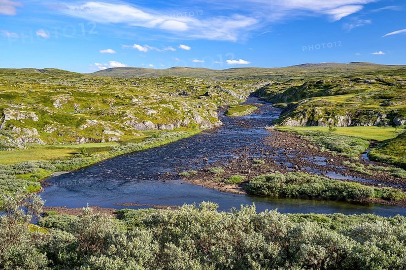 Vøringsfoss, Vestland, Norway, A wide river flows through a hilly, wild landscape under a blue sky in Hardangervidda