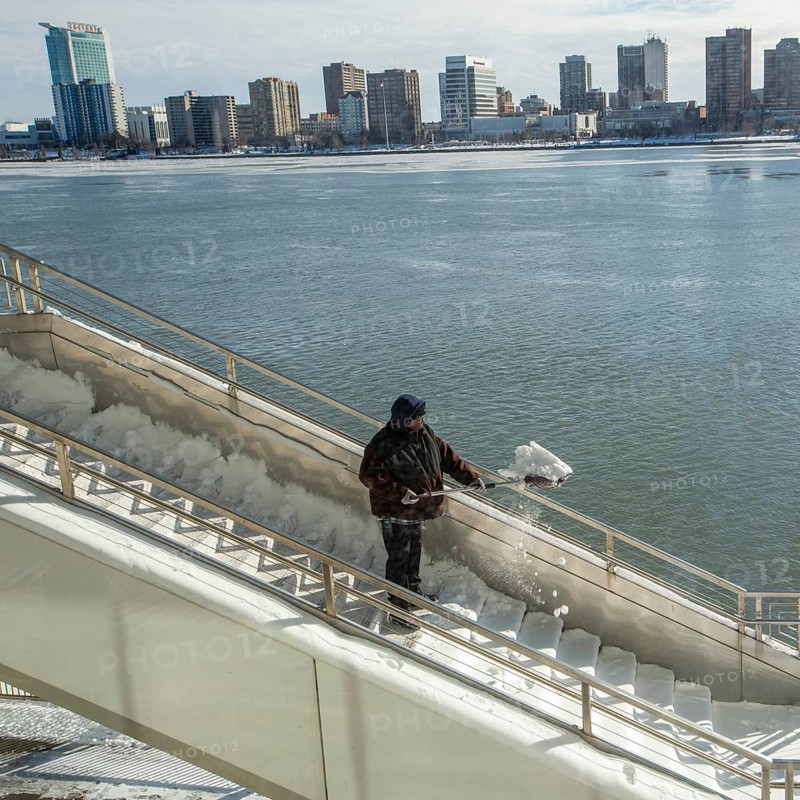 Detroit, Michigan USA - 15 January 2026 - A worker shovels snow from steps leading to Huntington Place convention center where the Detroit Auto Show is being held