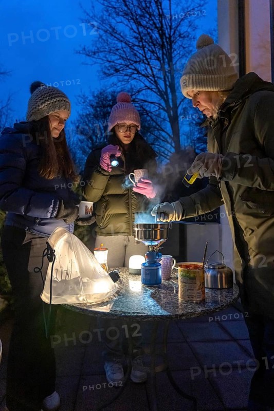 Symbolic picture blackout, extensive, prolonged power failure, in private surroundings, without electricity, heating, water, cooking, heating food and water with a gas-powered camping stove, on the balcony