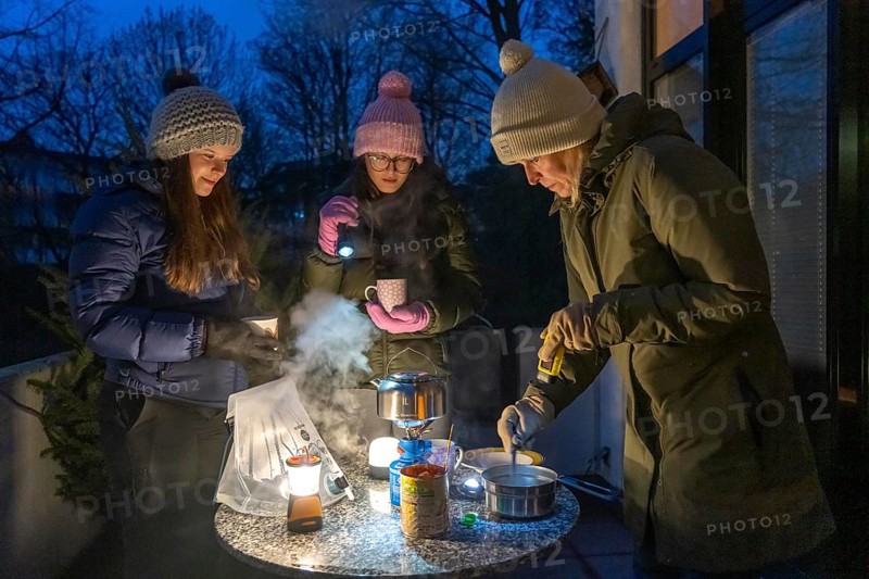 Symbolic picture blackout, extensive, prolonged power failure, in private surroundings, without electricity, heating, water, cooking, heating food and water with a gas-powered camping stove, on the balcony