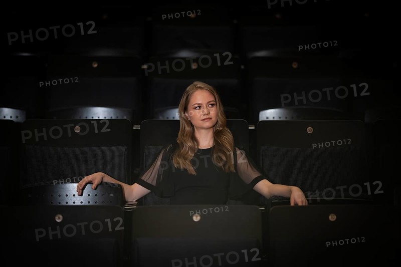 Young woman, pianist, in evening dress, sitting on chair in audience area, Stuttgart, Baden-Württemberg, Germany