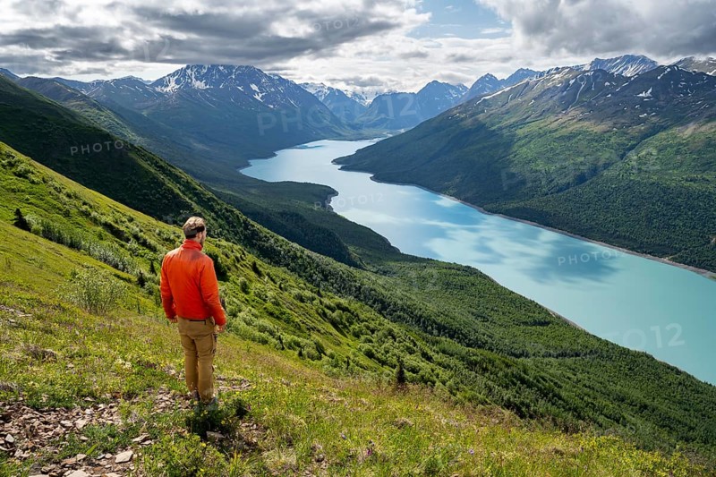 Mountaineer enjoys views of blue lake and mountains on Twin Peaks Trail, Eklutna Lake, Chugach Mountains, Chugach State Park, Alaska, USA