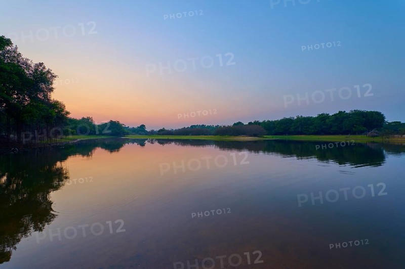 Gentle twilight to a calm lake, with trees on the horizon and blue sky, Fazenda Barranco Alto, Rio Negro, Pantanal, Mato Grosso, Brazil