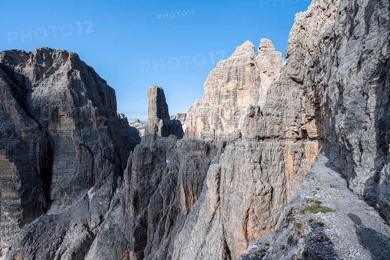 Trail along an exposed rock band on the secured Via Ferrata Bocciere Centrale via ferrata, spectacular mountain landscape with steep rocky peaks, Brenta-Adamello Natural Park, Trentino, Italy