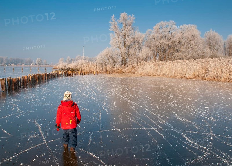 Child in red clothes walks across a frozen area of Dümmer Lake in a wintry landscape, Dümmer nature park Park, Lembruch, Lower Saxony, Germany