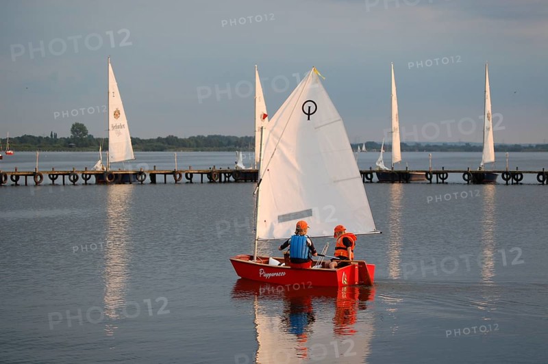 Two children 6 and 10 years old in a small red sailboat Optimist Jolle Opti on Lake Dümmer in calm skies, Dümmer nature park Park, Lembruch, Lower Saxony, Germany