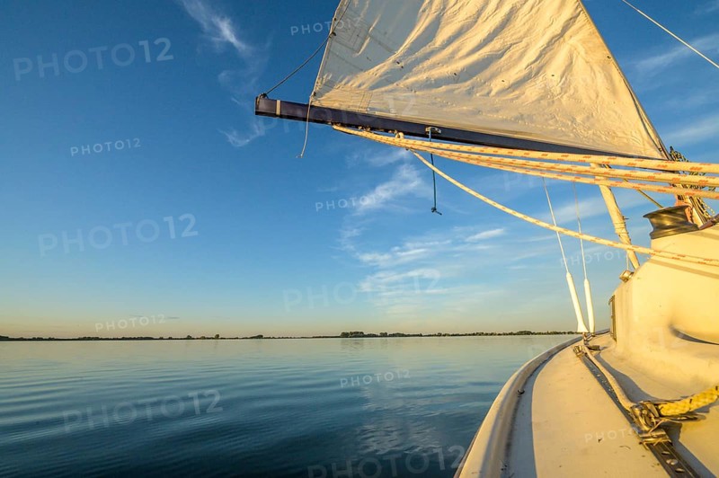 Sailing boat dinghy cruiser on calm Dümmer See, wide horizon, clear blue sky tint, Dümmer nature park Park, Lower Saxony, Germany