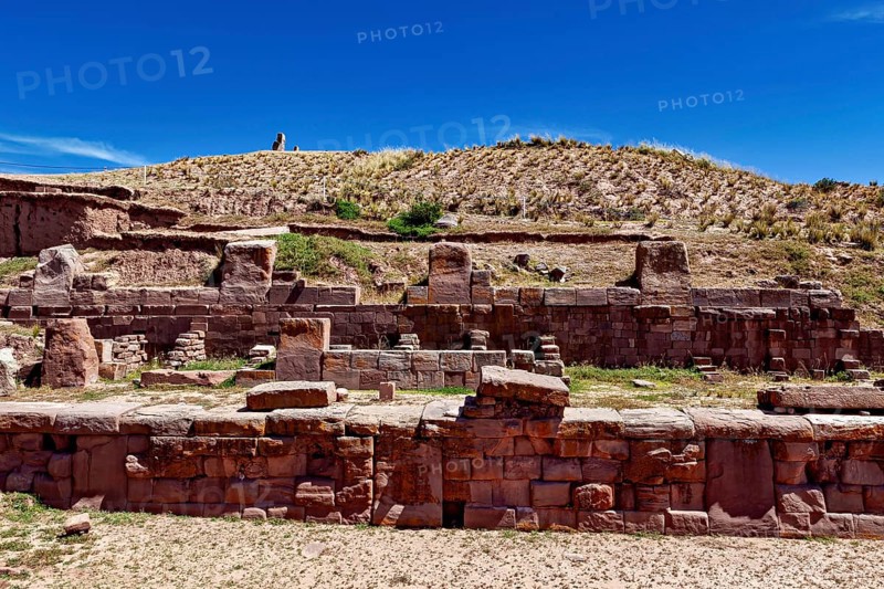 Ancient stone ruins under a clear blue sky surrounded by dry, grassy landscape, The archaeological site with the ruins of Tiwanaku in Bolivia