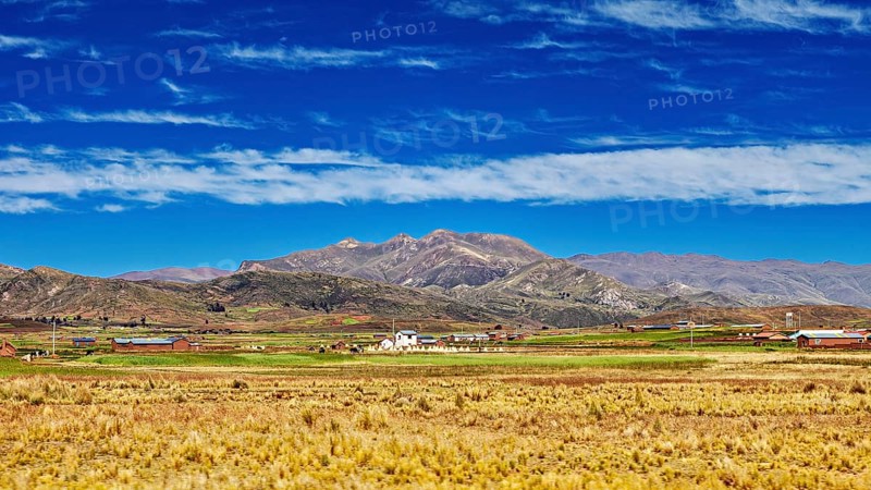 Wide fields in front of a mountain range under a cloudy sky, The Altiplano landscape in the Andes of Bolivia