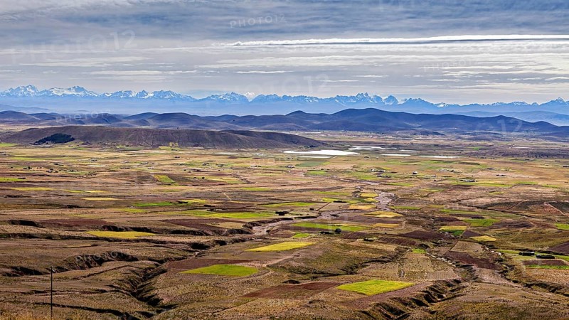 Extensive fields with mountains on the horizon and cloudy sky, the Altiplano landscape in the Andes of Bolivia