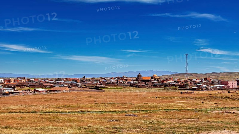 View of a village with church and antenna under wide sky surrounded by open fields, The city of Tiwanaku near the ruins of Tiwanaku in Bolivia