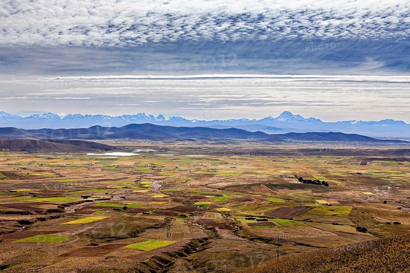 Wide panorama with fields and mountains under a cloudy sky, The Altiplano landscape in the Andes of Bolivia