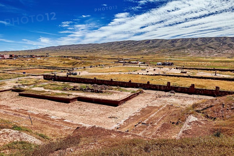 Extensive valley with ruins in the foreground and a mountain range on the horizon, the archaeological site with the ruins of Tiwanaku in Bolivia