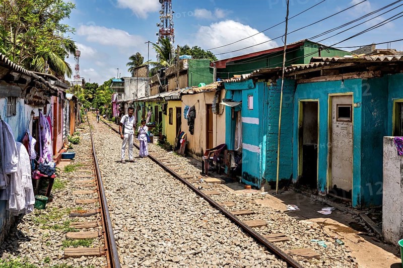 Narrow street along railroad tracks flanked by colorful houses under clear skies, railway line in the historic Slave Island district of Colombo Sri Lanka