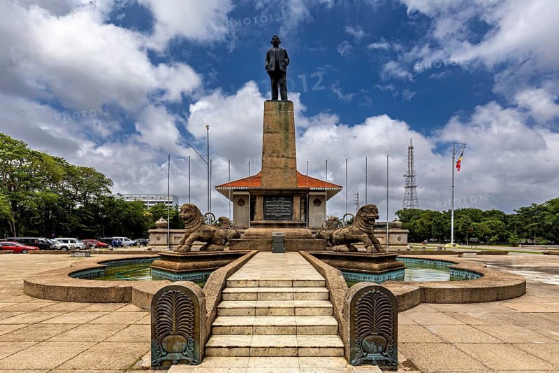 A monument with a statue on a pedestal surrounded by lions and a fountain on a cloudy day, Colombo City Hall Sri Lanka
