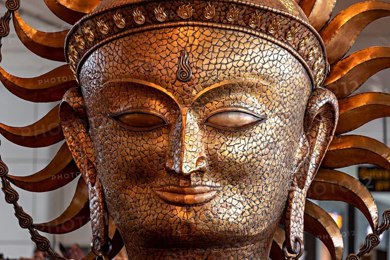 Golden sculpture of a face with solar elements, ancient art style with ornate details, portrait of a goddess in Colombo airport in Sri Lanka